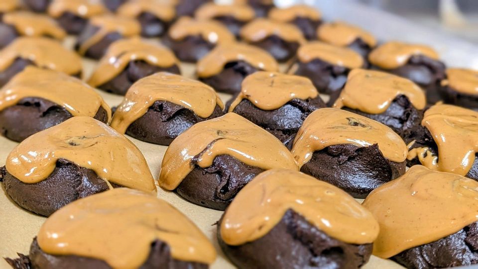 Dark cookies topped with a light tan swirl on a baking tray
