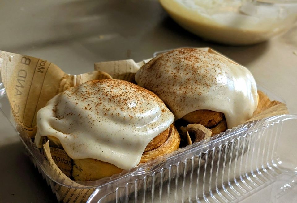 Two swirled rolls with a thick white glaze and a dusting of spice