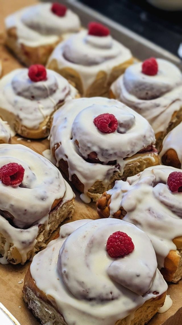 Glazed swirled rolls, each topped with a red berry