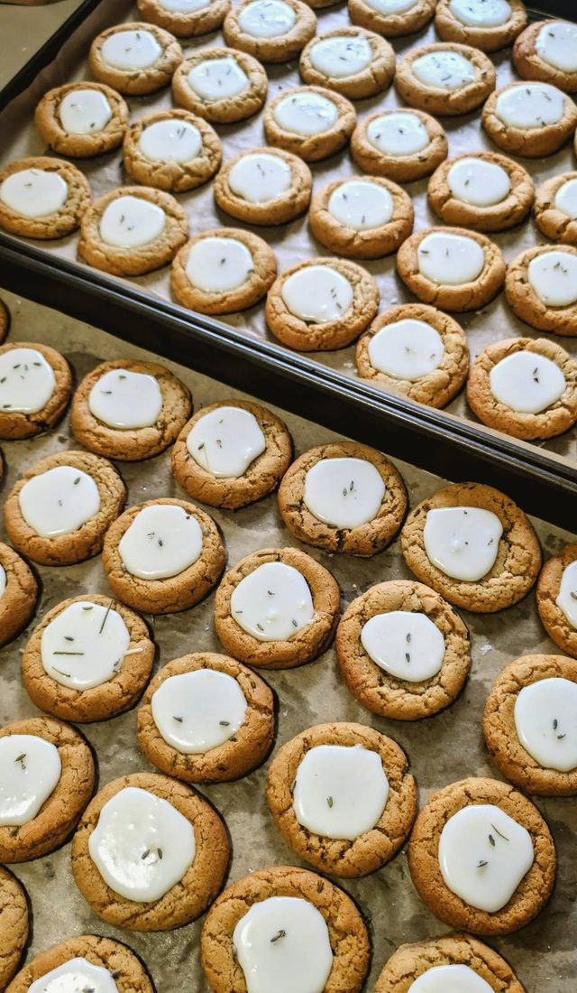 Rows of cookies with white icing centers on baking trays